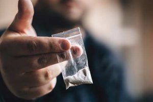 a bag of heroin being held out Heroin addiction
