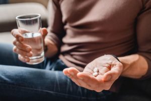 man holding pills and water