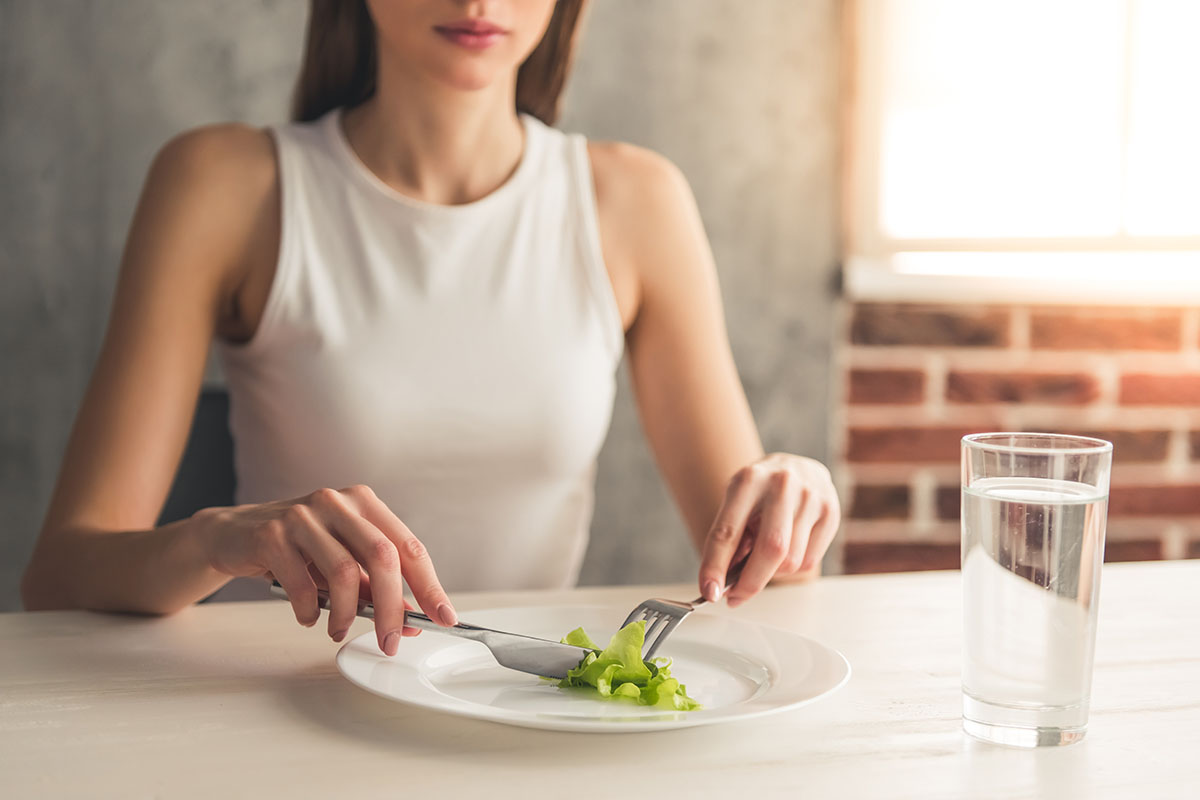 woman in white shirt showing signs of an eating disorder