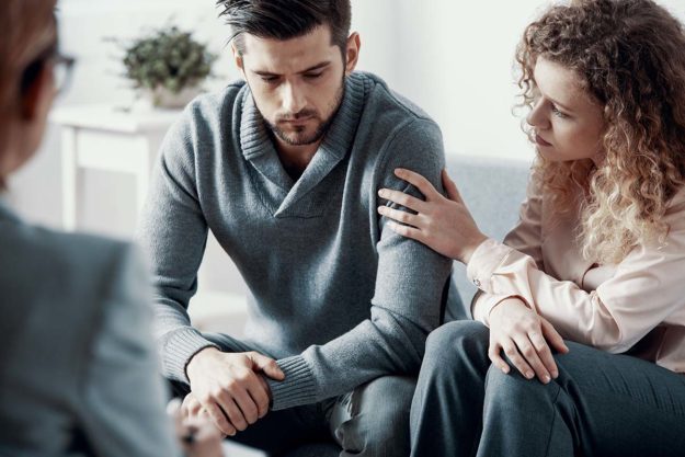 How Much is Couples Therapy And How to Pay For it Couple sitting on couch, having a touch discussion in couples therapy
