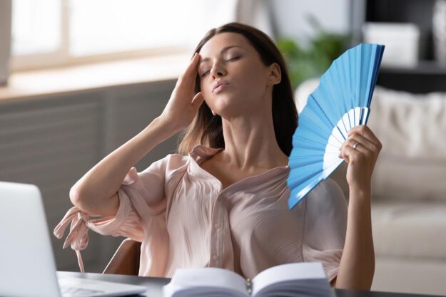 Woman fans herself as she deals with hormonal issues after quitting alcohol