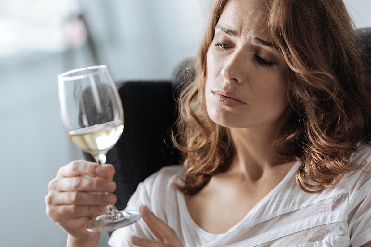 Why Do Females Have Intense Alcohol Cravings Woman holds glass of wine up to face, wondering why females have intense alcohol cravings
