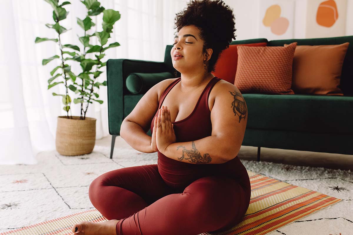 Woman sits on floor doing yoga pose, enjoying positive effects of yoga therapy