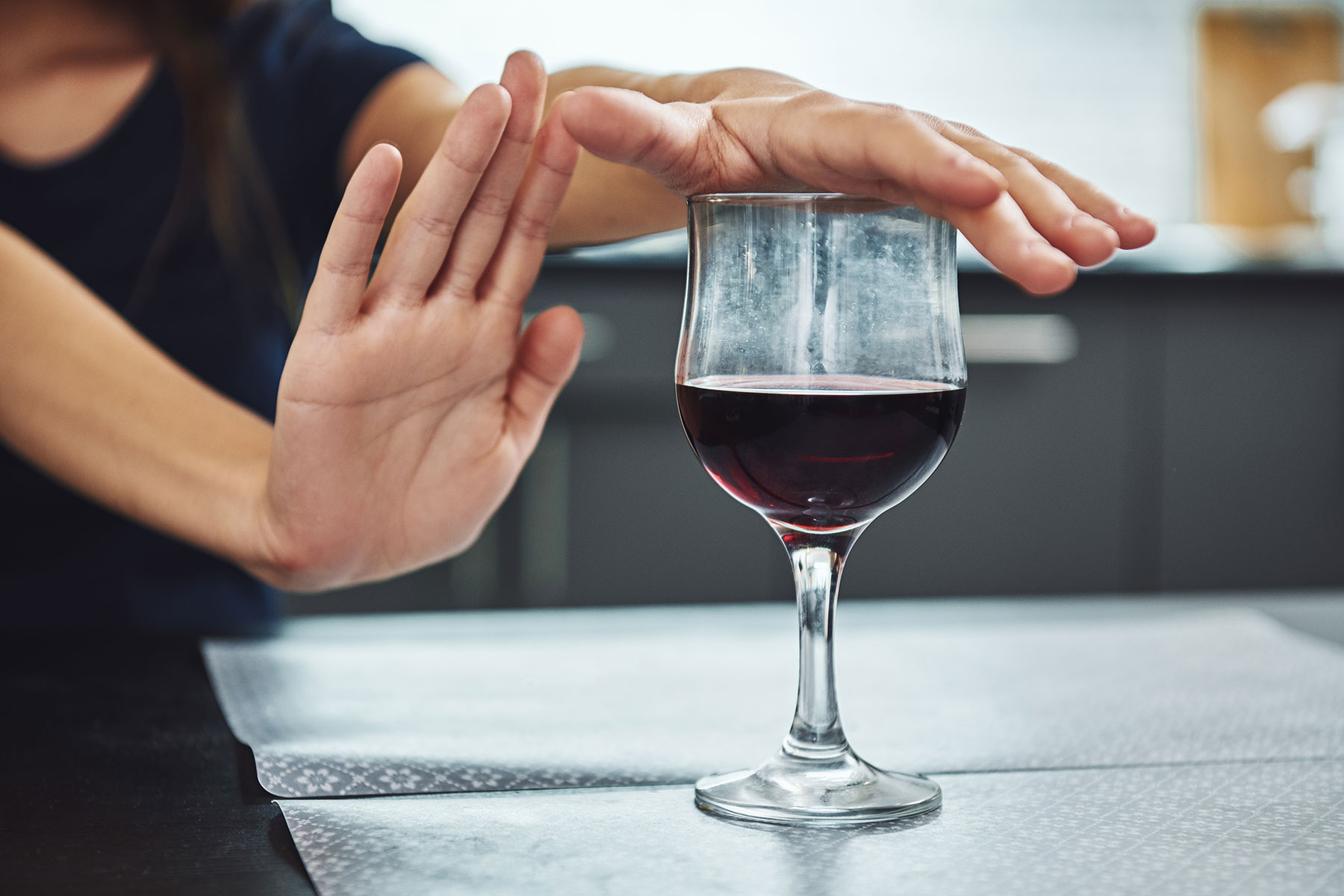 Woman puts hand over wine class as she says no, while trying to manage alcohol cravings