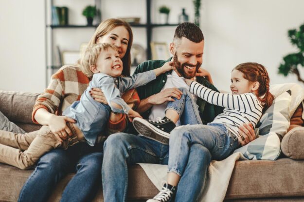 7 Family Therapy Techniques to Help Promote Healthy Relationships Family huddles up on couch after learning healthy family therapy techniques