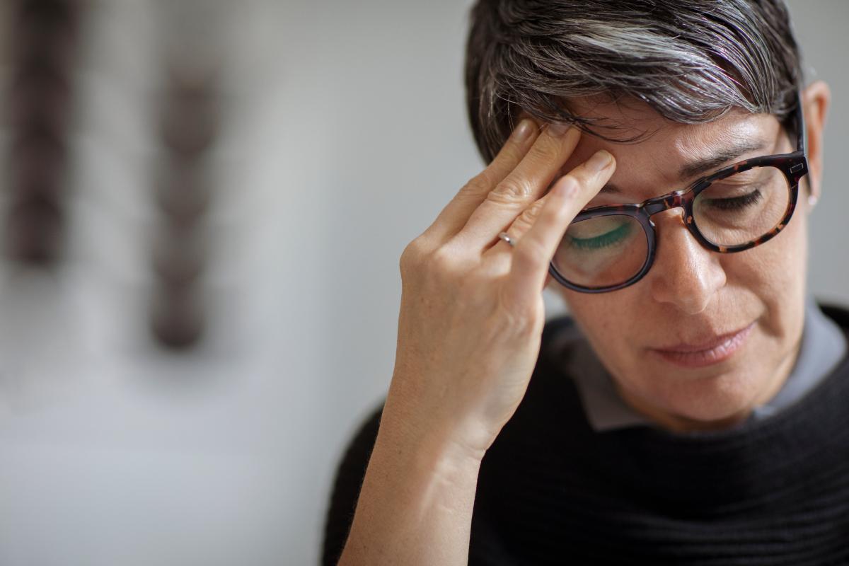 What Is the CBT Triangle_ Woman rubs forehead, nursing a headache while thinking about cbt triangles