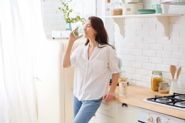 Psychosis Recovery Timeline- Getting Back to Normal Woman drinks glass of water in kitchen as she continues her psychosis recovery timeline