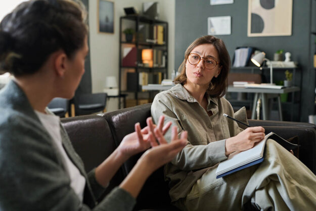 Importance Of Mental Health Counseling Person discusses the importance of mental health counseling with their therapist on couch