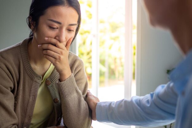 Woman begins to cry as father comforts her while they discuss acoa personality types