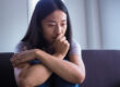 Woman sits on couch and ponders symptoms of meth use